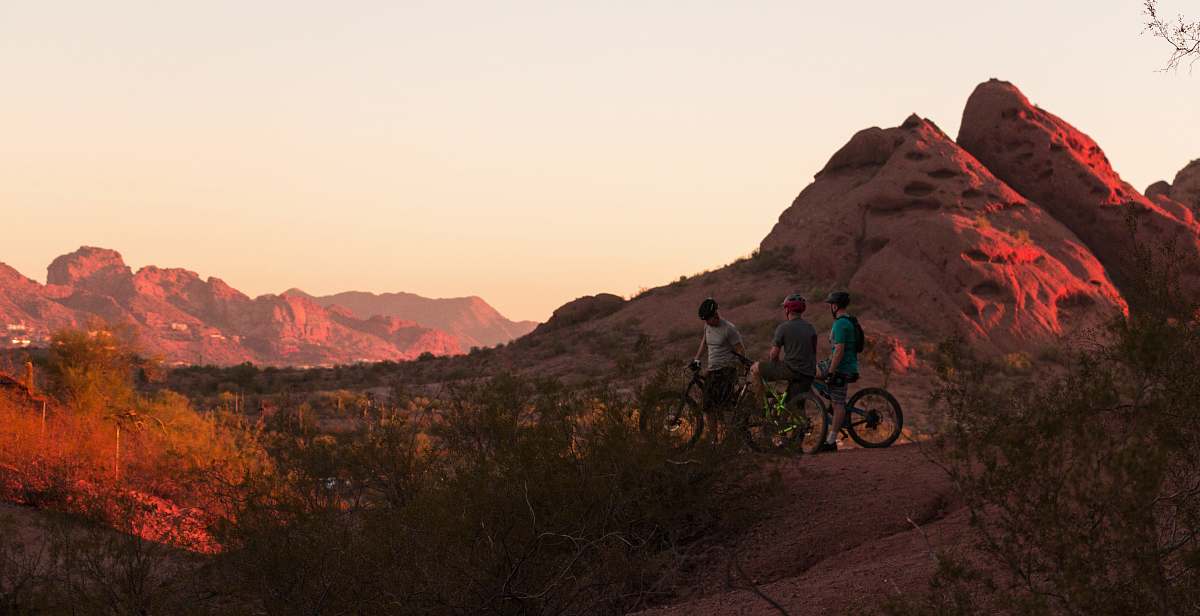 biking three men with their bicycle looking at rock formations \ trail